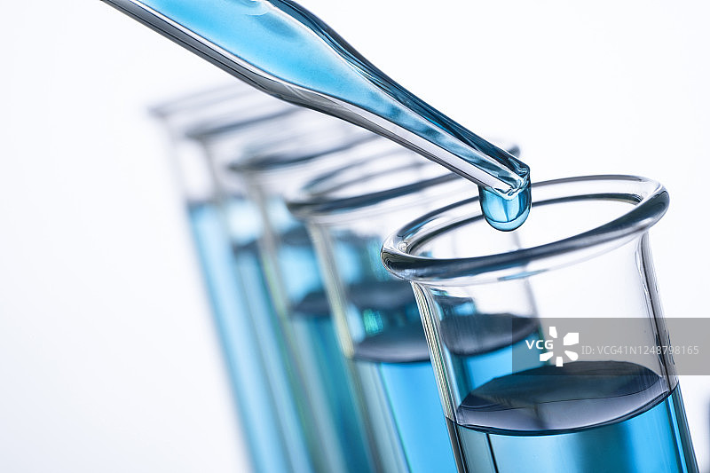 蓝色水滴在移液器和试管上的特写图片素材