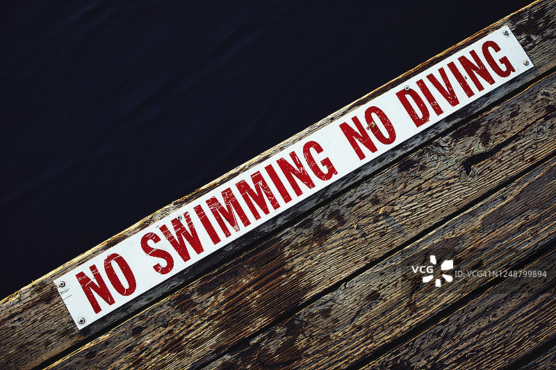 木制码头边缘的禁止游泳和潜水标志图片素材
