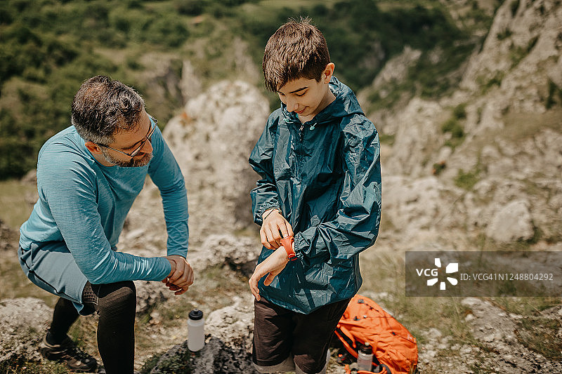 父亲和儿子在岩石山上查看时间图片素材