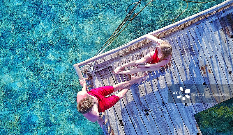 平静的游泳平台：情侣在木制平台上放松身心图片素材