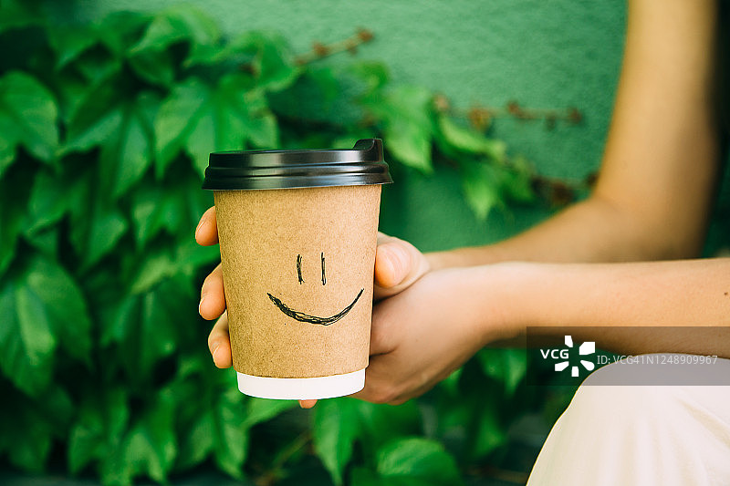 一名女子拿着一个棕色纸杯图片素材