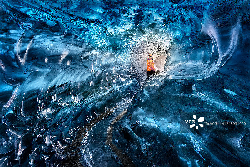 男人在冰岛瓦特纳冰川探索蓝色冰洞图片素材