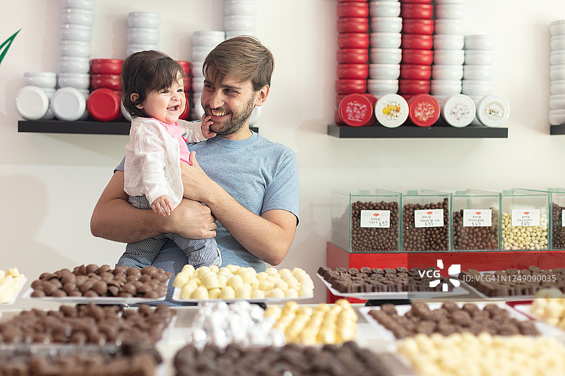 父亲和快乐的女婴在巧克力店图片素材