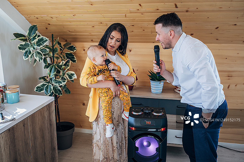 快乐的父母和他们的男婴在家唱卡拉OK图片素材