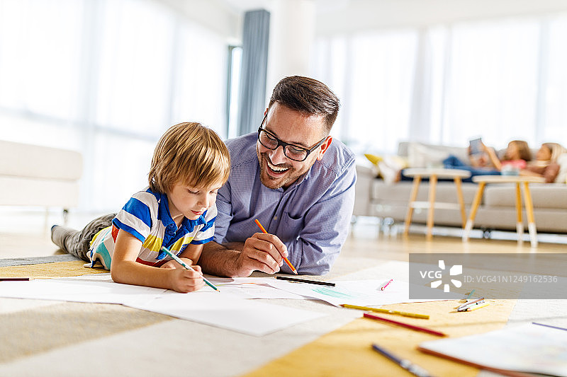 父子在家中地板上涂色图片素材