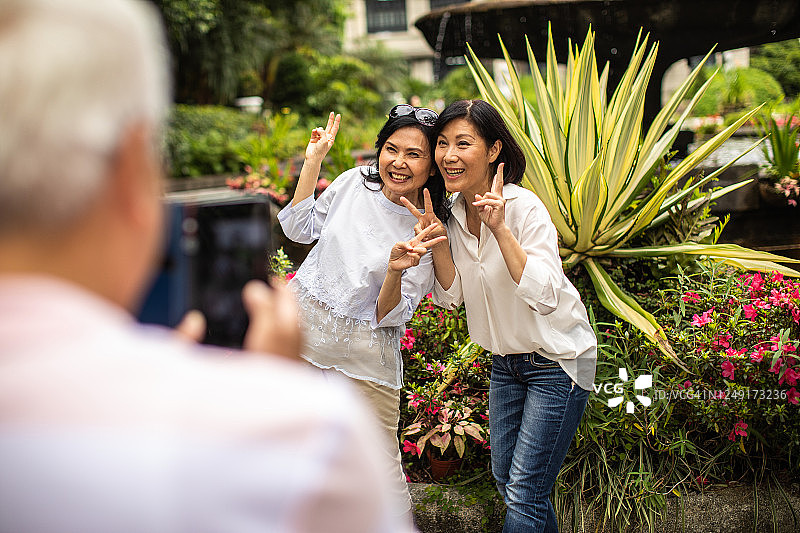 男子在公园里拍摄两位年长的中国台湾朋友图片素材