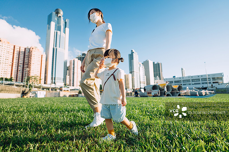 佩戴口罩的亚洲母女在城市公园里散步图片素材