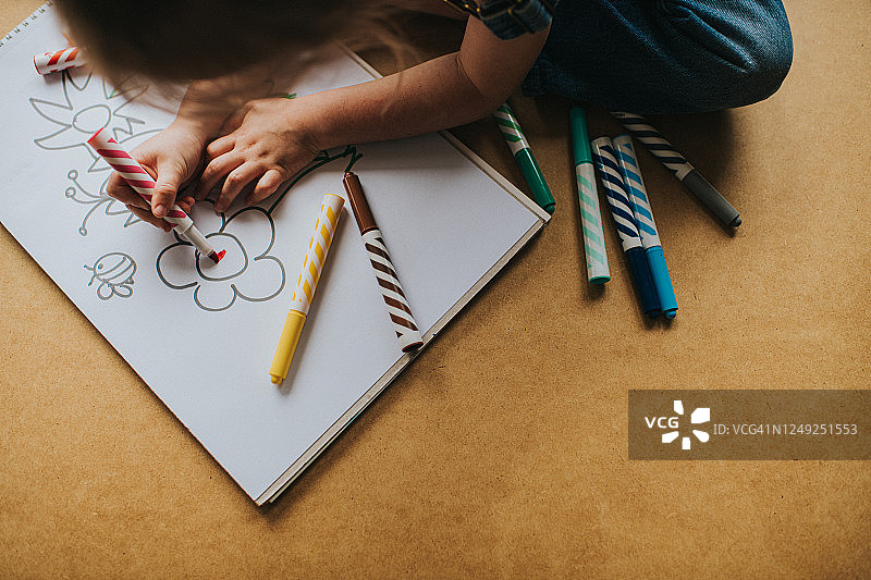 小女孩用彩色笔在素描本上绘画图片素材