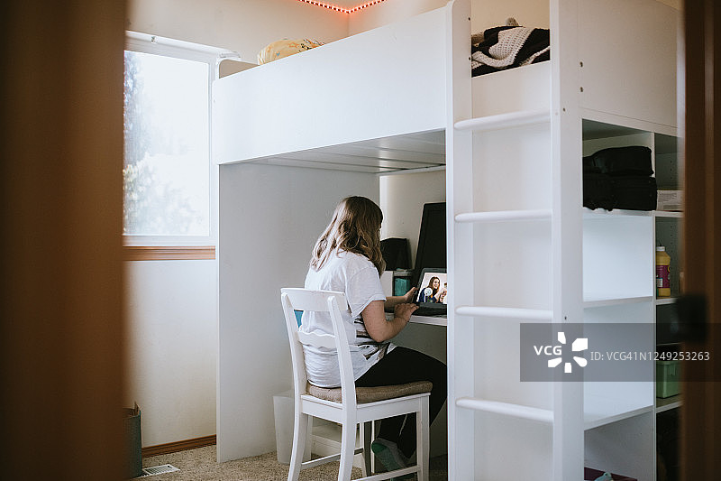 在卧室里用笔记本电脑上网课的女孩图片素材