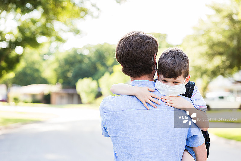 父亲抱着戴防护口罩的年幼儿子图片素材
