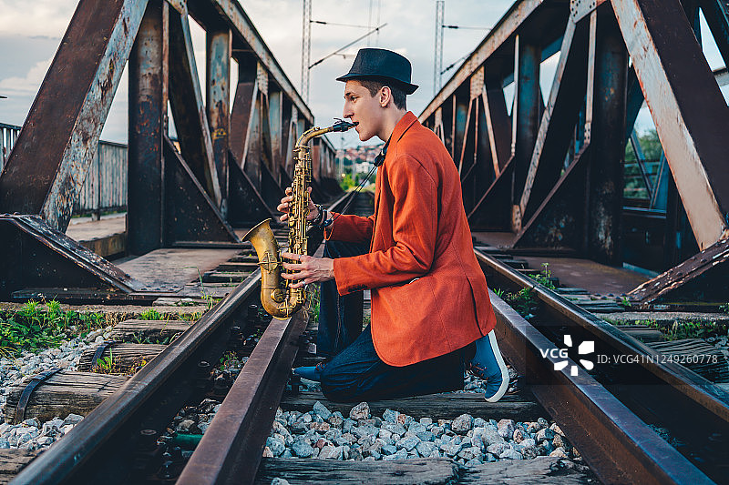 在铁路桥上吹萨克斯的男人图片素材