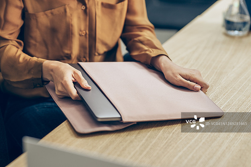 女商人从桌上的电脑包里取出笔记本电脑图片素材