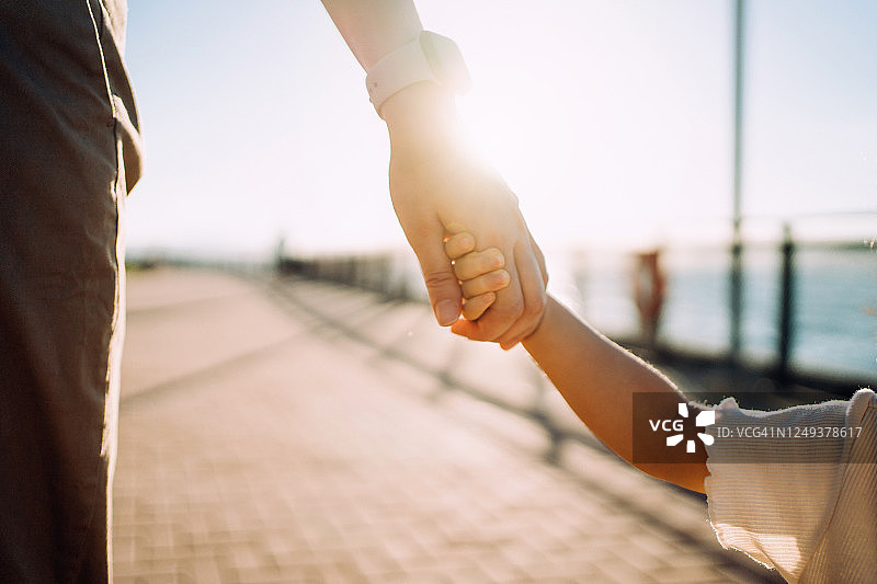 年轻的亚洲母亲与女儿手牵手在公园长廊日落时享受亲子时光图片素材