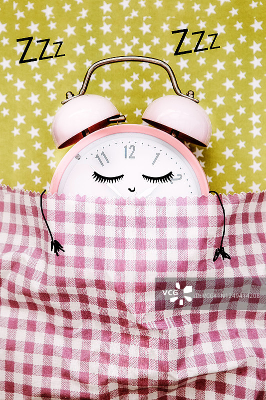 粉色闹钟在床上睡觉图片素材