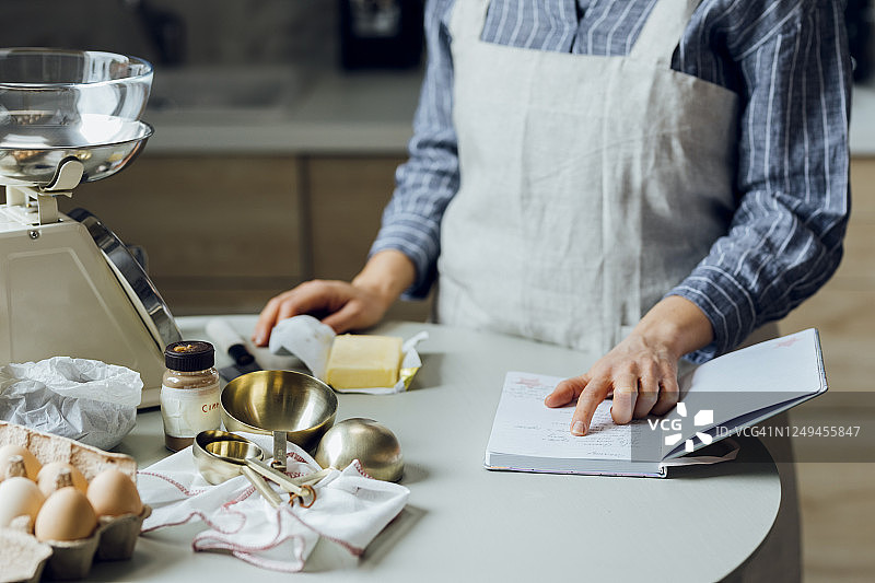 在家烘焙：年轻女人在厨房里阅读食谱图片素材