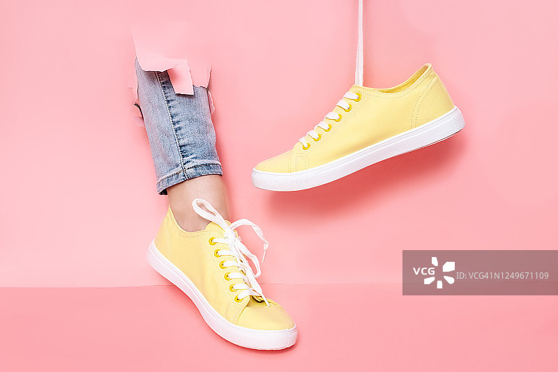 穿着时尚运动鞋的女人靠近彩色墙壁，特写。留有文字空间图片素材