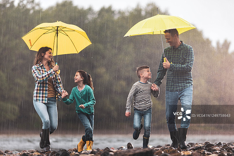 幸福的一家人在雨天河岸边奔跑玩耍图片素材