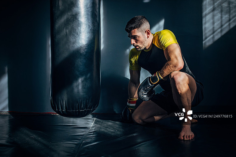 年轻男人跪在运动垫上练习跆拳道图片素材