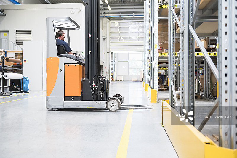 在高层货架仓库中使用叉车的工人图片素材
