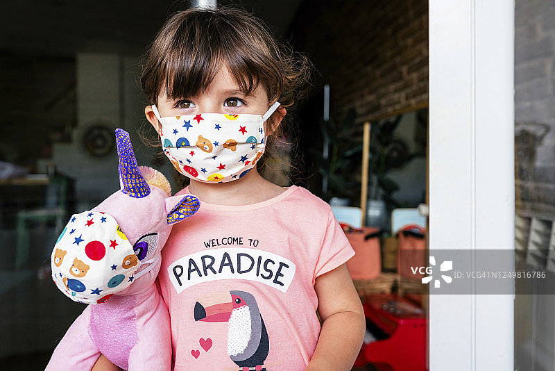 戴着彩色面具和独角兽玩具的女孩肖像图片素材