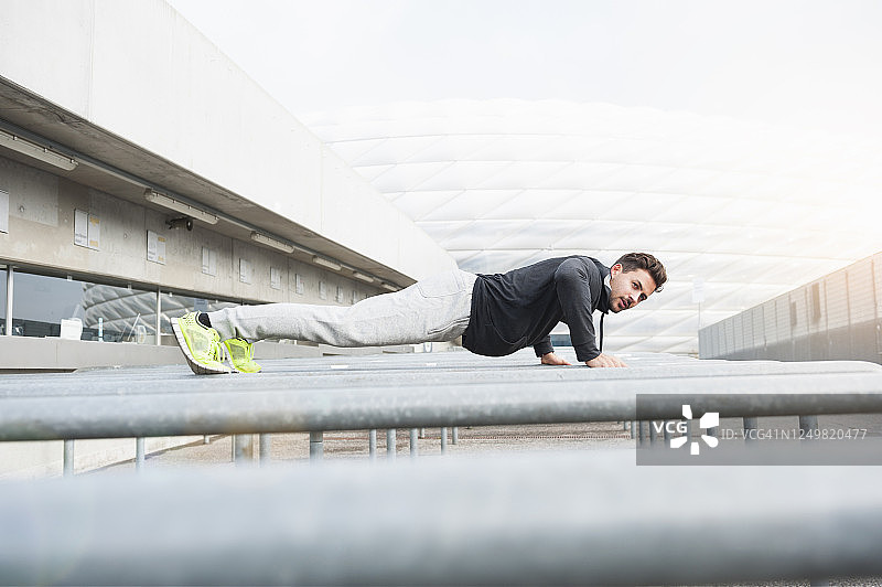 在金属杠上做俯卧撑的年轻人图片素材