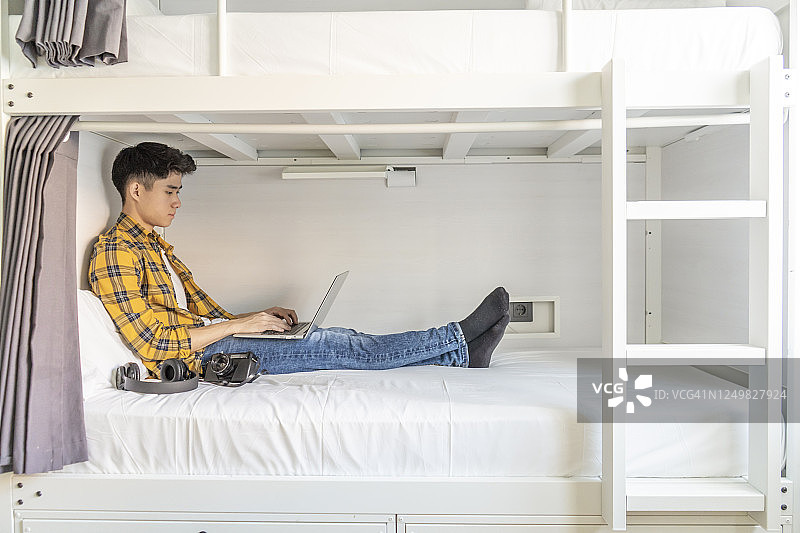在旅馆床上使用笔记本电脑的年轻游客图片素材