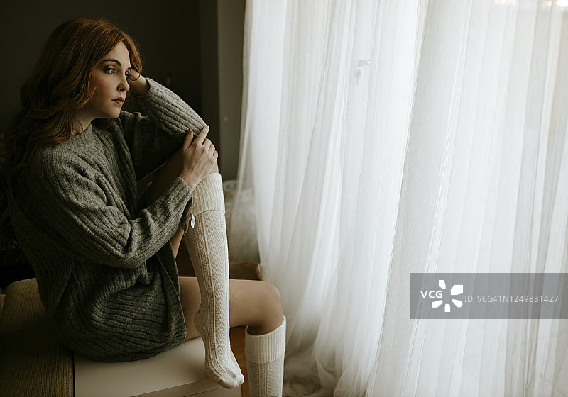 在家望向窗外的严肃金发女人图片素材