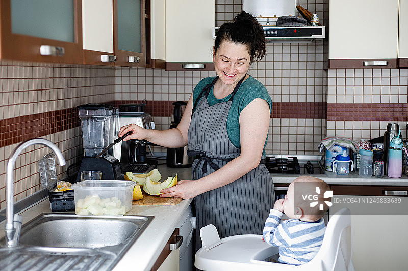 年轻女子和男婴在厨房准备奶昔图片素材