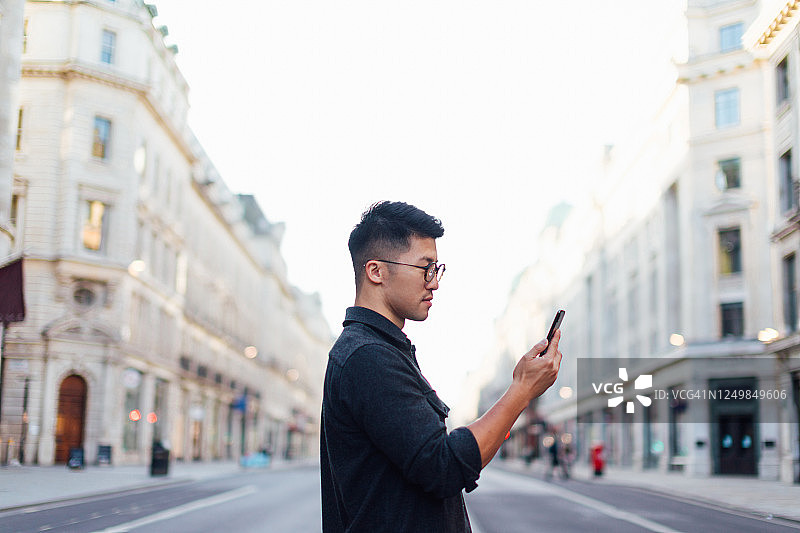 自信的男人用智能手机探索城市图片素材