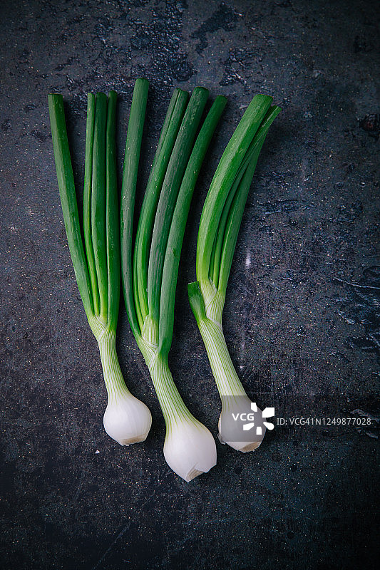 旧背景上的新鲜绿色洋葱图片素材