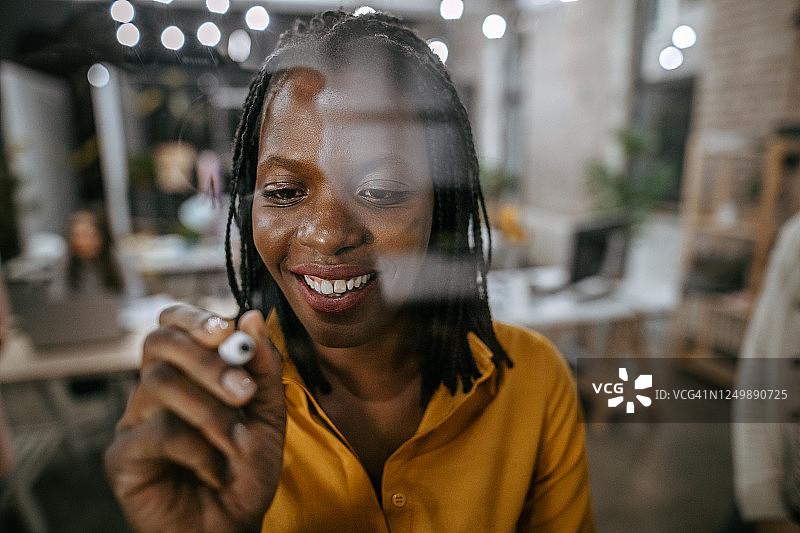 在玻璃板上书写的非洲裔女子图片素材