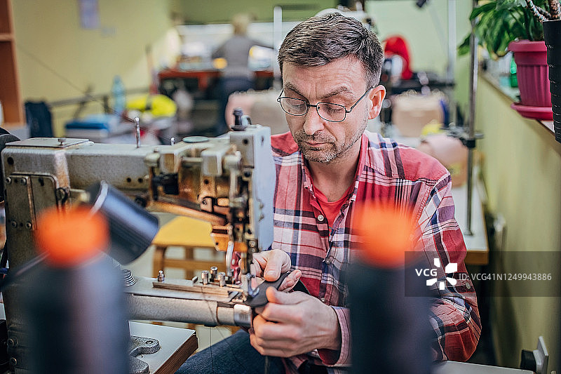 在缝纫机上工作的年长男人图片素材