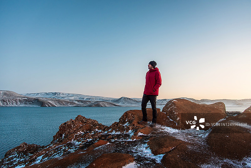 冬季在冰岛克莱瓦湖欣赏雪山美景的男人图片素材