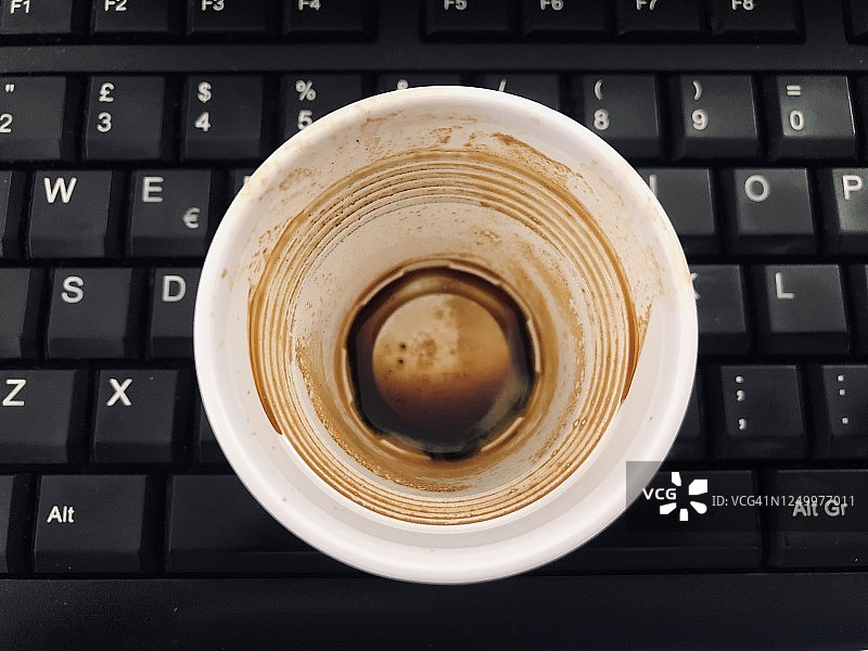 有咬痕的意式甜点咖啡空杯与黑色键盘图片素材