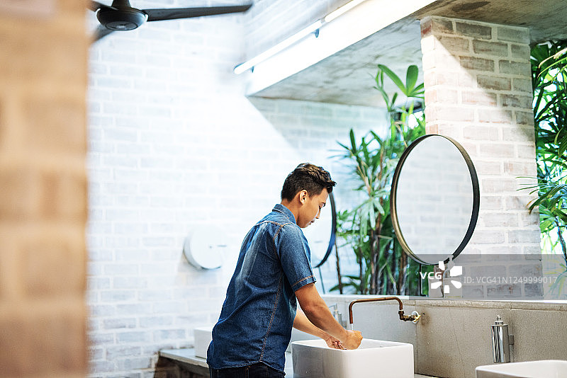 在新冠疫情期间于公共洗手间洗手的年轻男人图片素材