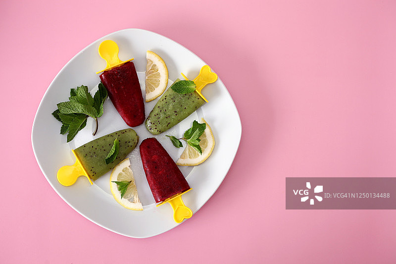 猕猴桃草莓汁自制冰淇淋，粉色背景上点缀柠檬片和薄荷叶图片素材