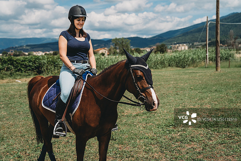 年轻女子在马术学校骑马图片素材