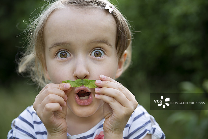 淘气的孩子用直升机种子当胡子图片素材