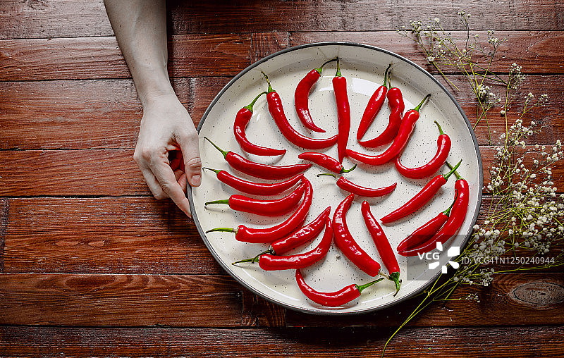 辛辣红辣椒在木质背景白色托盘中图片素材