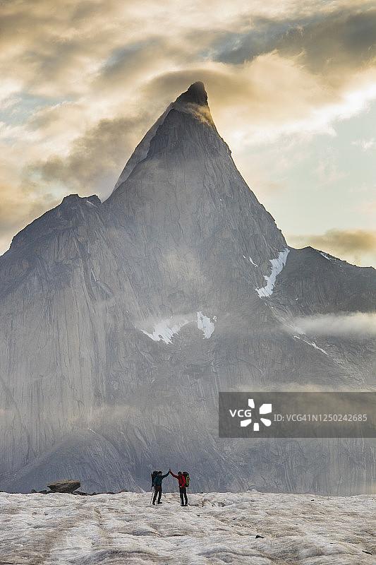 在壮丽山景下击掌庆贺的两位背包客图片素材