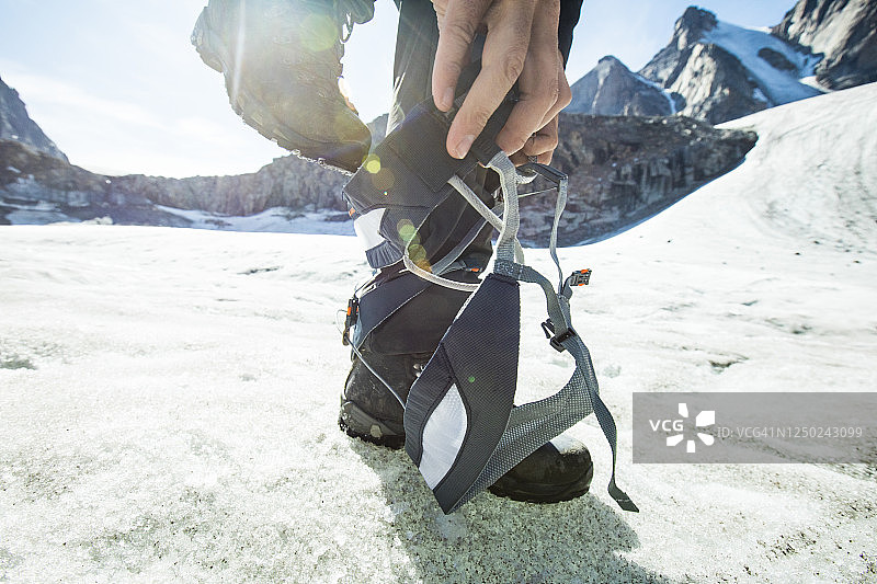 登山者踩入登山安全带的低角度特写图片素材