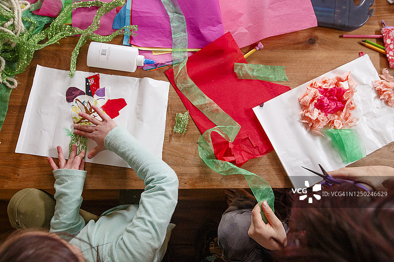 俯视角度下的两个孩子在木桌上进行艺术创作图片素材