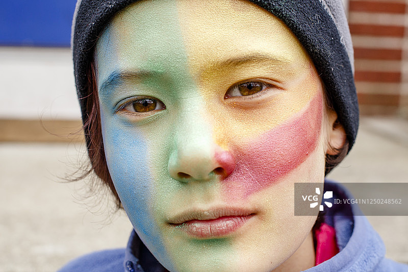 化着彩色脸部彩绘，目光直视的美丽男孩肖像图片素材