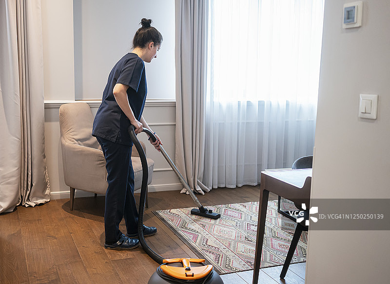 客房服务员在酒店房间吸尘图片素材