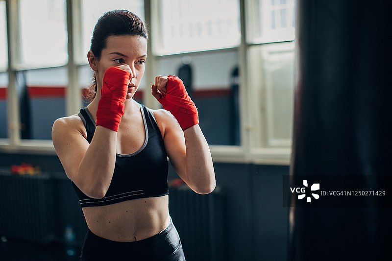 年轻女子对着沙袋练习拳击图片素材