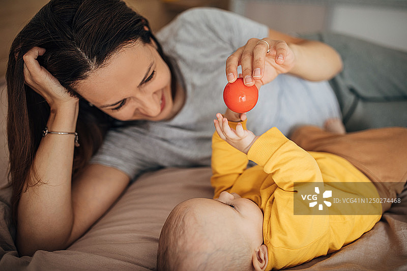 母亲在卧室的床上和儿子玩耍图片素材