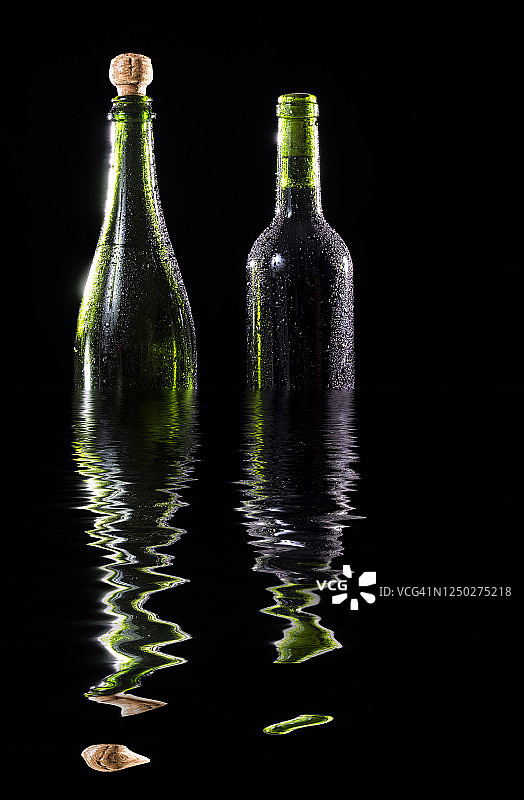 黑色背景上反射在水面上的葡萄酒和香槟酒瓶图片素材