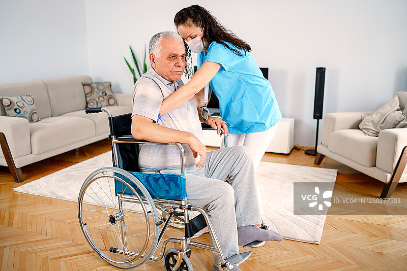身体残疾：悲伤的老年男人握着护理人员的手，试图起身图片素材