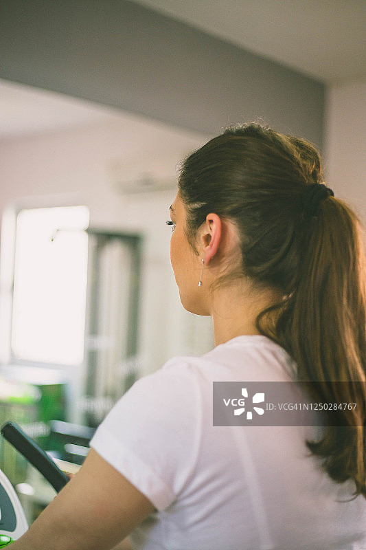 在健身房自行车上训练的有魅力的年轻女人的脚。在健身房骑自行车锻炼的健身女人。图片素材