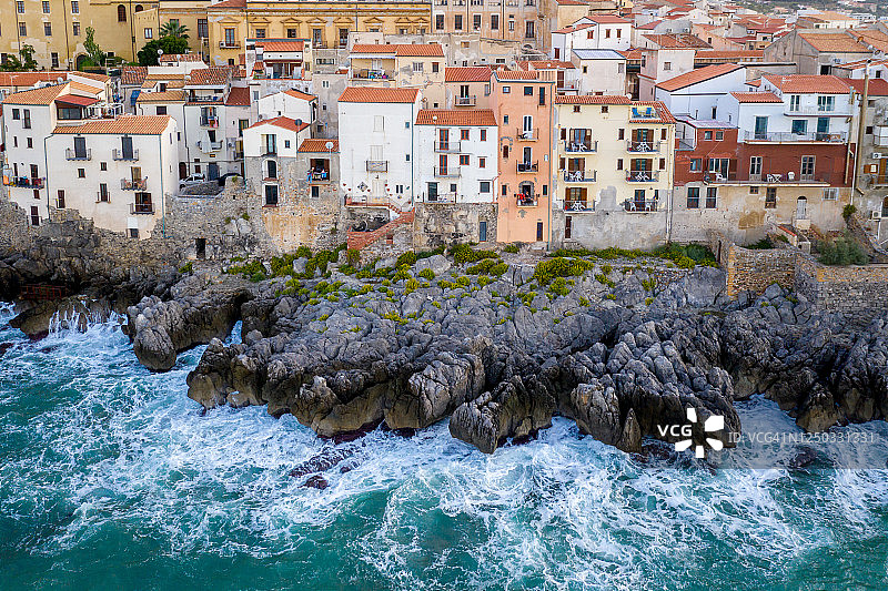 大风暴天气中，从海上拍摄的切法卢岩石海岸和房屋的航拍景色，意大利西西里岛图片素材